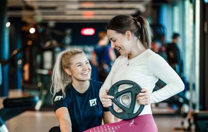 Personal trainer showing female client how to do lunge with plates